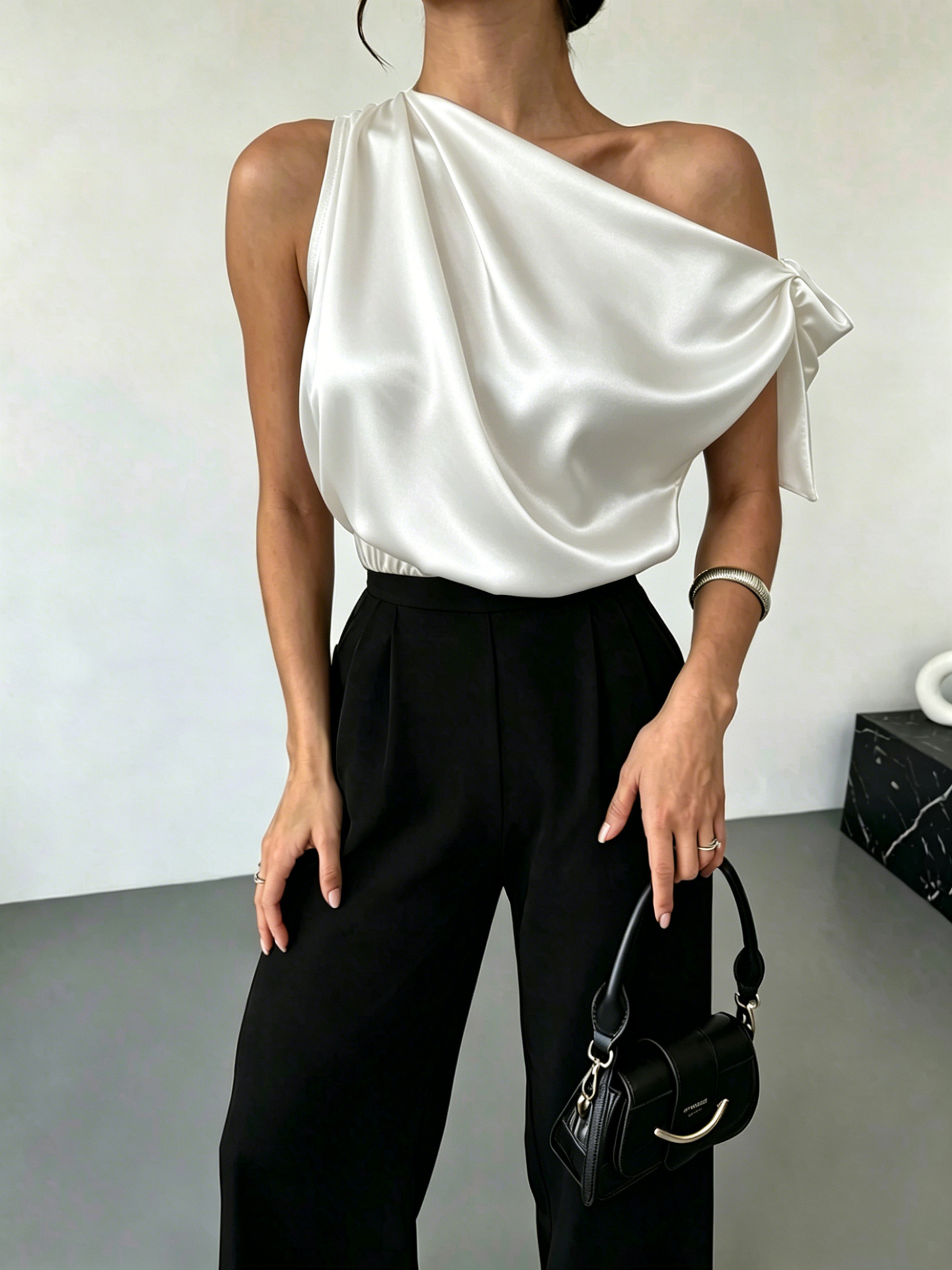 Women's satin off-shoulder bow blouse in Black – asymmetrical top styled for night out with mini skirt and heels