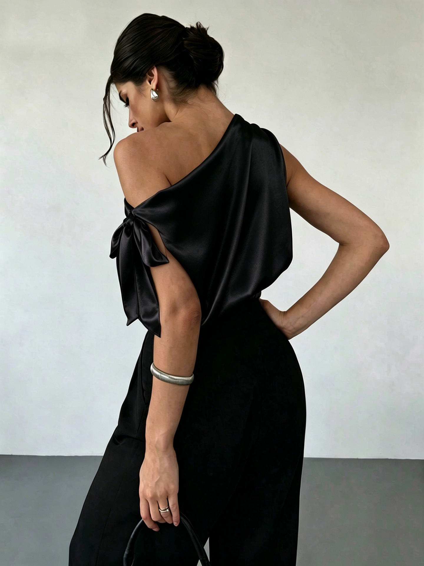 Women's satin off-shoulder asymmetrical blouse in Black – bow detail close-up showing satin fabric and bow construction
