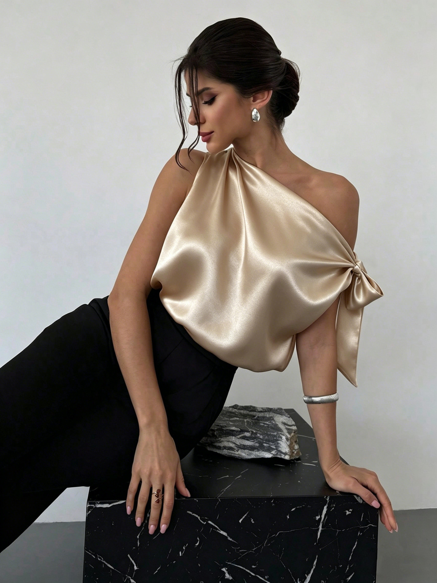 Women's satin off-shoulder blouse in Apricot – asymmetrical bow top styled for special occasion with heels
