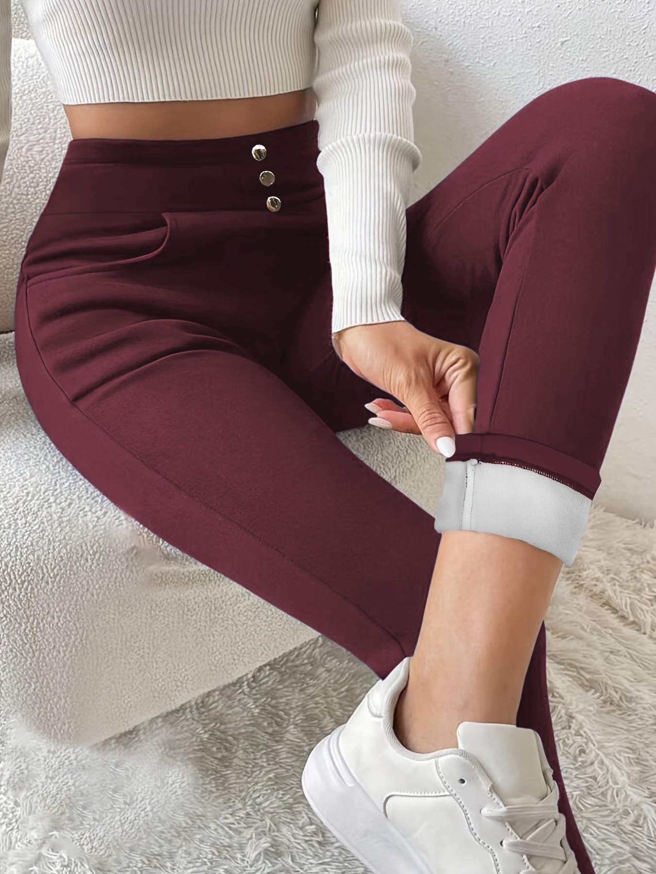 Wine-red leggings close-up showing the high waistband, three button details and turned-up cuff with light-coloured lining