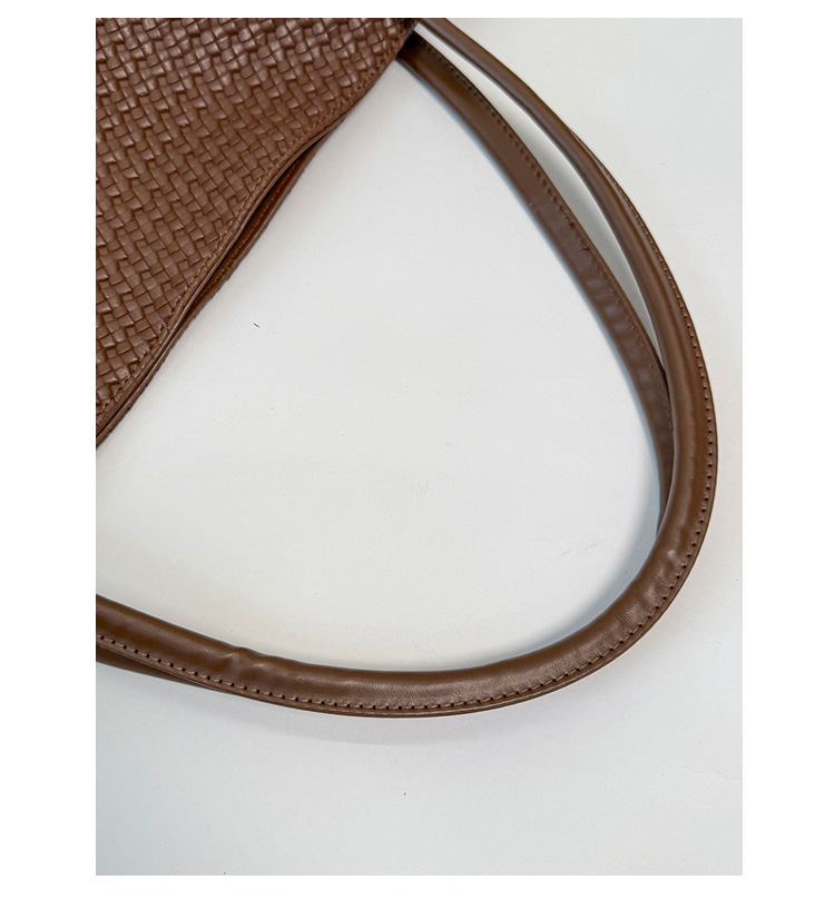 Close-up of the brown tote's smooth stitched handles beside its woven-look PU surface